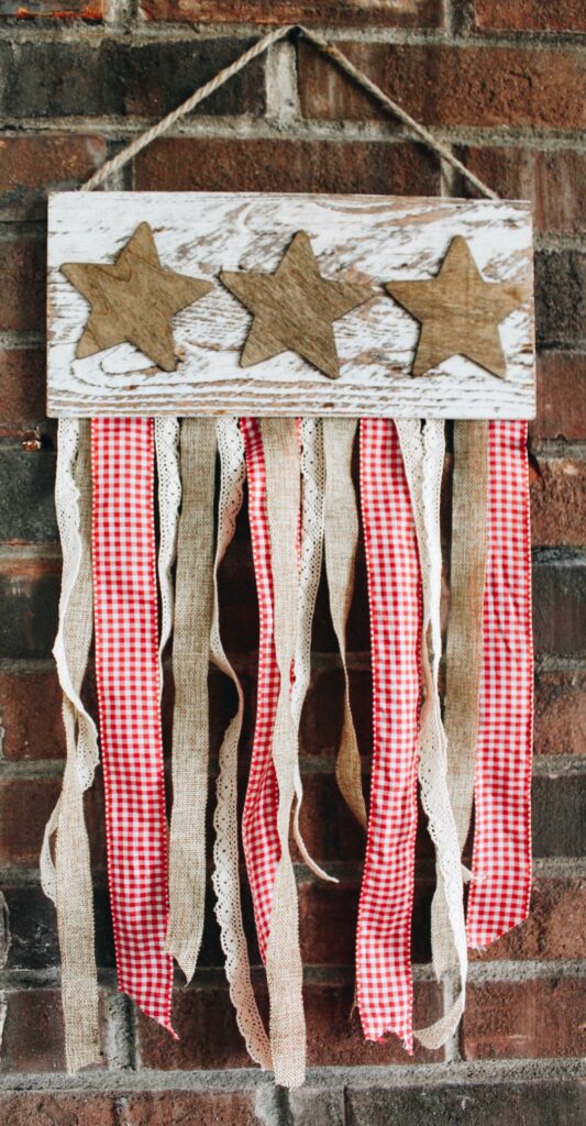 rustic wood star plank with ribbon. hanging on a brick background