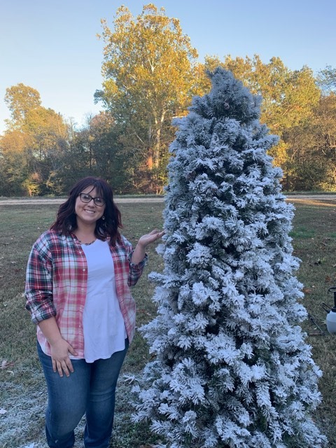 woman standing next to artificial flocked christmas tree