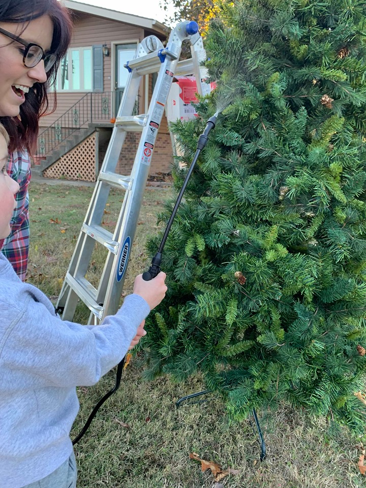 spraying artificial tree with water before applying snoflock