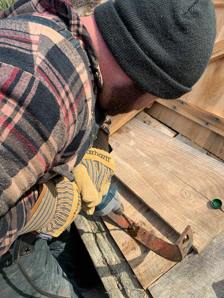 man drilling a hole into rusty metal for a upcycled kitchen island dresser 