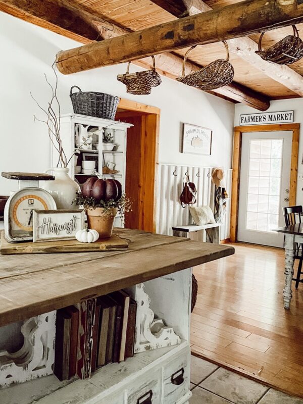 rustic country kitchen island with old books on lower shelv and pumpkin rustic vignette